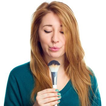 Girl is applying makeup using brush, isolated over white