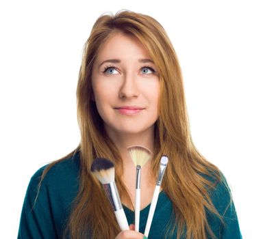 Girl is applying makeup using brush, isolated over white