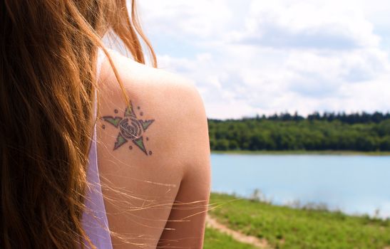 Outdoor shot of a young woman shoulder with tattoo
