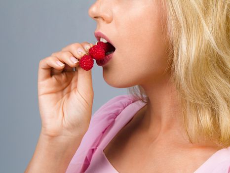 Beautiful woman eating sweet raspberries