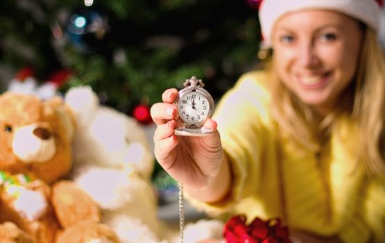 New Year clock in woman hands on christmas tree background