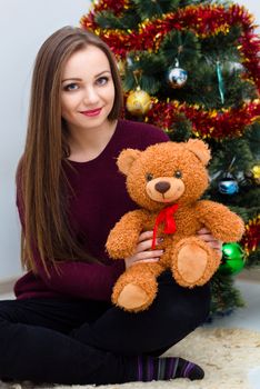 Woman with teddy bear near the Christmas tree at room
