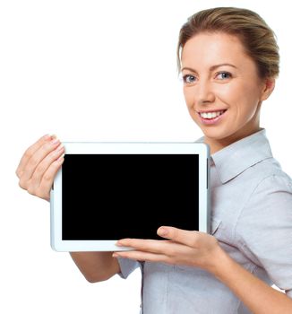 Young cheerful woman is showing blank tablet, isolated over white