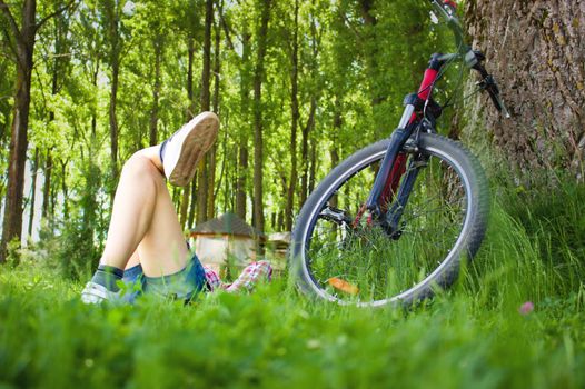 Young cyclist relaxation lying in the fresh green grass 
