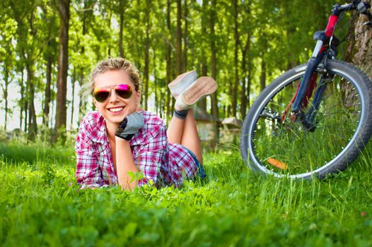 Young cyclist relaxation lying in the fresh green grass