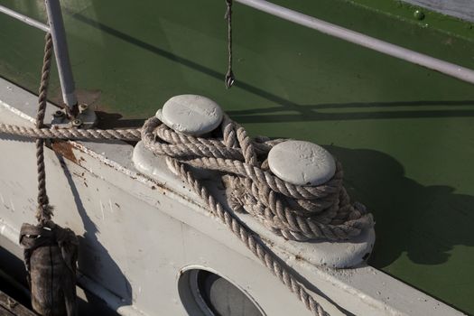 A fender on a boat and some rope to keep it safe in harbor