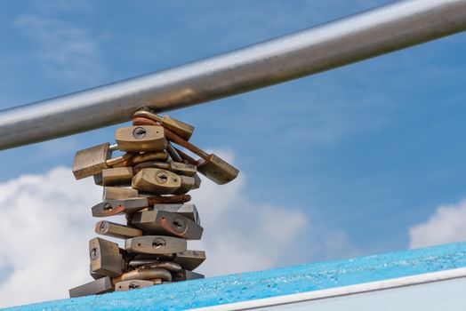 Many locks locked around a pole symbolizing relationships meant to last. A blue sky with clouds in the background.