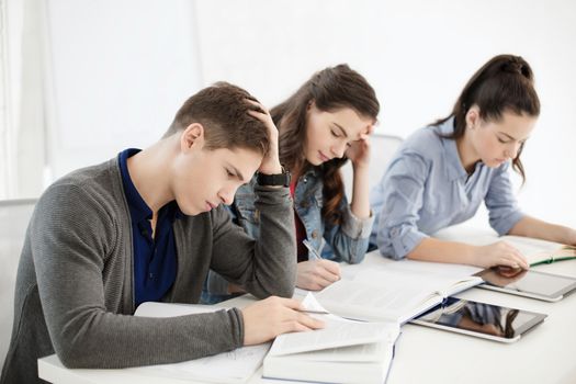 school and education concept - group of tired students with notebooks at school