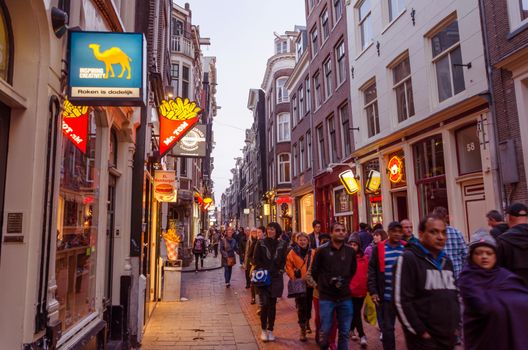 Amsterdam, Netherlands - May 8, 2015: People visit red-light district on May 8, 2015 in Amsterdam. This district consists of a network of alleys containing approximately three hundred one-room cabins rented by prostitutes