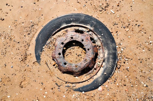 Rusted wheel in sand on the beach