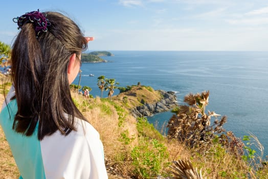 Back of the women tourist looking at beautiful nature sea and island with a happy on the mountain viewpoint at Laem Phromthep Cape a famous attractions of Phuket Province in Thailand