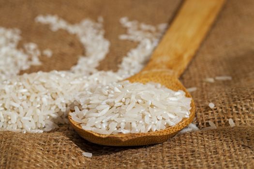 rice grains on a wooden spoon - derevyannnoy spoon scattered grains of rice. Close-up.