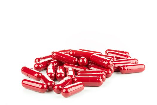 Three Red Pills (Capsules) with Many in Background Isolated on a White
