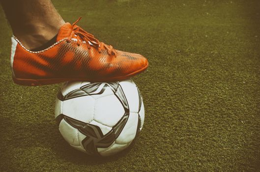 Photograph of a foot and a soccer ball on the grass