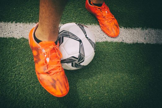 Photograph of a soccer player´s feet and soccer ball on a green artificial grass