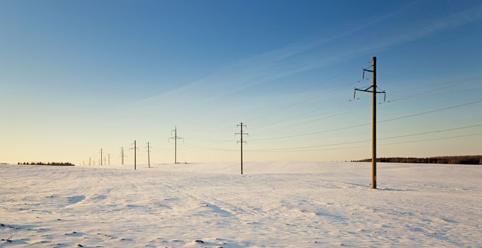  the electric columns which are standing in the field. winter.