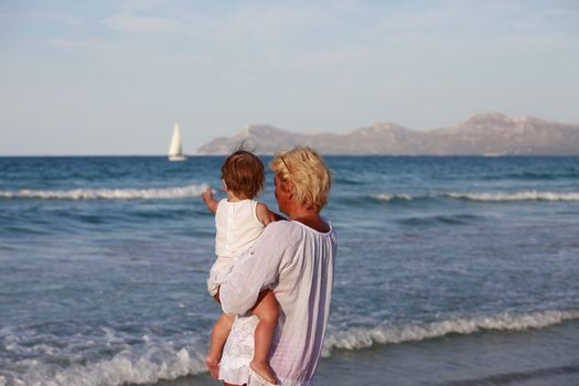 Grandmother with a little granddaughter on the beach