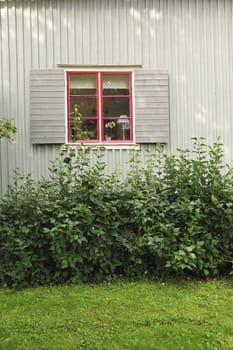 Grey painted wooden wall of the house with closed windows that have opened shutters.