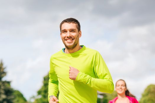 fitness, sport, friendship and lifestyle concept - smiling couple running outdoors