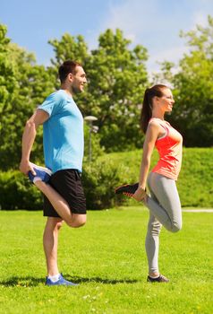 fitness, sport, training and lifestyle concept - smiling couple stretching outdoors