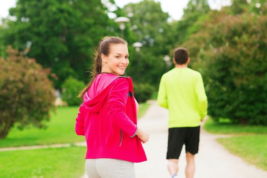 fitness, sport, friendship and lifestyle concept - smiling couple running outdoors