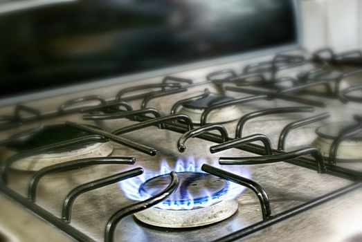 Photograph of a lighted metal gas stove and blue fire flame