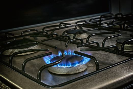 Photograph of a lighted metal gas stove and blue fire flame