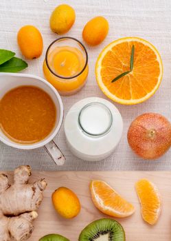 Breakfast with orange juice, oranges, oranges slice, passion fruit , ginger,tomato and Kiwi set up on wooden table .