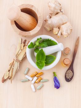 Alternative health care fresh herbal ,dry herbal and herbal capsule with mortar on wooden background.