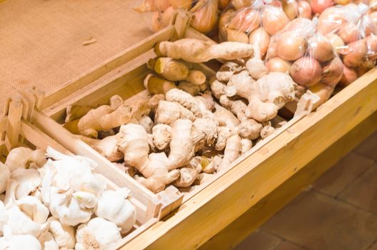Many Italian garlic onions and ginger root for sale at a farmers market.