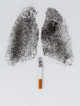 Shape of lungs with charcoal powder and cigarette on white background