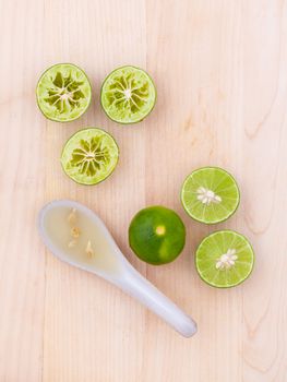 Fresh Lime juice in spoon and lime slice on wooden background.