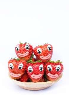 stack of red strawberries on wooden scale. Fruit with eyes and mouths isolated on white background