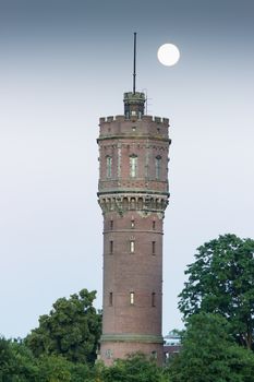 Brick watertower as building with full moon and trees