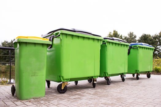 Greeen garbage containers in a row along street