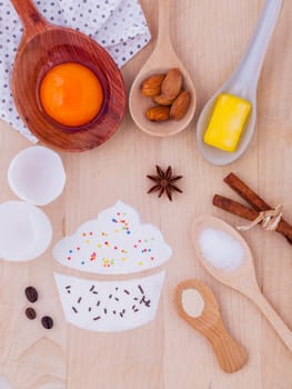 The ingredients of cup cake and the shape of cup cake with topping on wooden table .