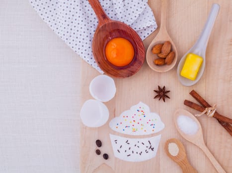 The ingredients of cup cake and the shape of cup cake with topping on wooden table .