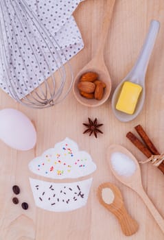 The ingredients of cup cake and the shape of cup cake with topping on wooden table .