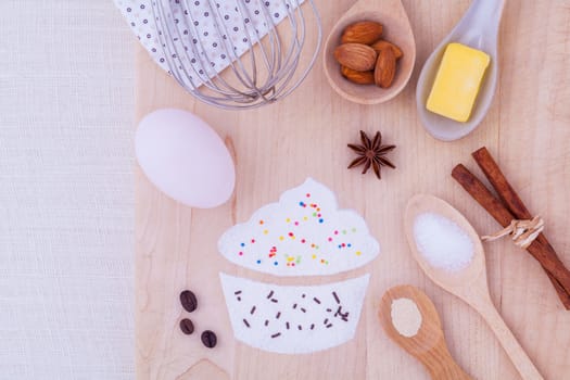 The ingredients of cup cake and the shape of cup cake with topping on wooden table .