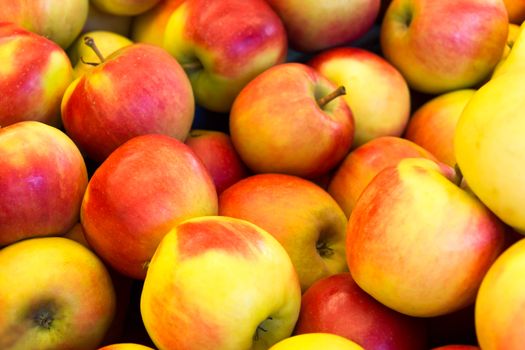 Many piled red with yellow apples at market