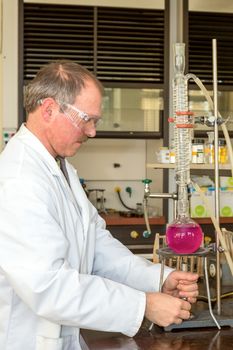 Chemist heating liquid in round-bottom flask for research in education