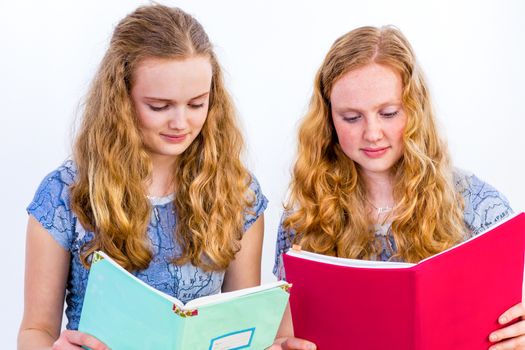 Two caucasian teenage schoolgirls reading books isolated on white background