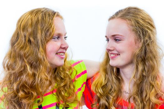 Two caucasian teenage girls embracing each other and laughing having fun  isolated on white background