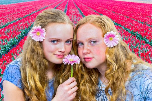 Two caucasian teenage girls in front of red tulip field in holland