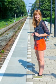 Caucasian redhead teenage girl standing at station waiting on train