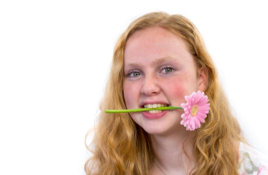 Caucasian teenage girl with pink flower in mouth isolated on grey white background