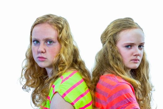 Two angry european teenage sisters with backs touching isolated on white background