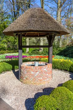 New brick waterwell with bucket in park in netherlands