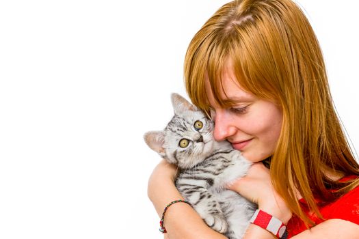 European red haired teenage girl hugging and loving young silver tabby cat isolated on white background