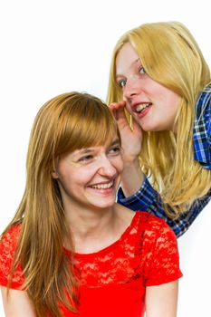 Blonde caucasian teenage girl whispering in ear of redhead girlfriend isolated on white background